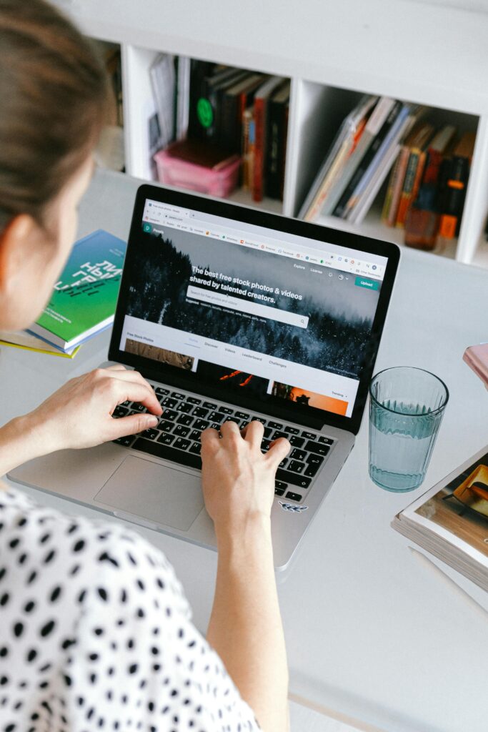 A woman working on her laptop at a desk, browsing the internet in a home office setting.